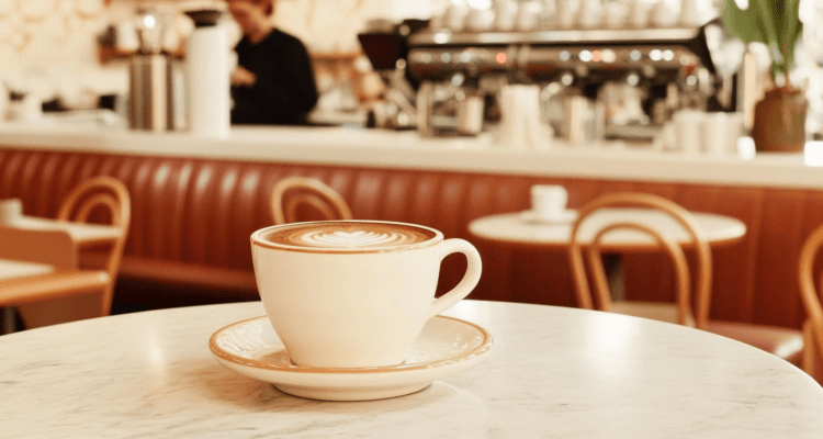 Cinematic shot of a freshly brewed espresso served in a small white cup on a saucer, placed on a polished wooden café table.